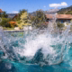 Wasserschwall mit spritzenden Tropfen über der türkisfarbenen Wasserfläche eines Timberra Naturpools.